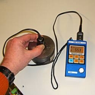 Das Materialstärkenmessgerät PCE-TG100 beim messen einer Stahlplatte
