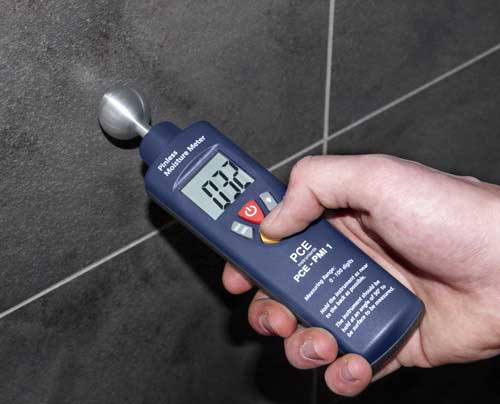 Das Materialfeuchte-Messger�t bei der Messung einer Wand mit Fliesen
